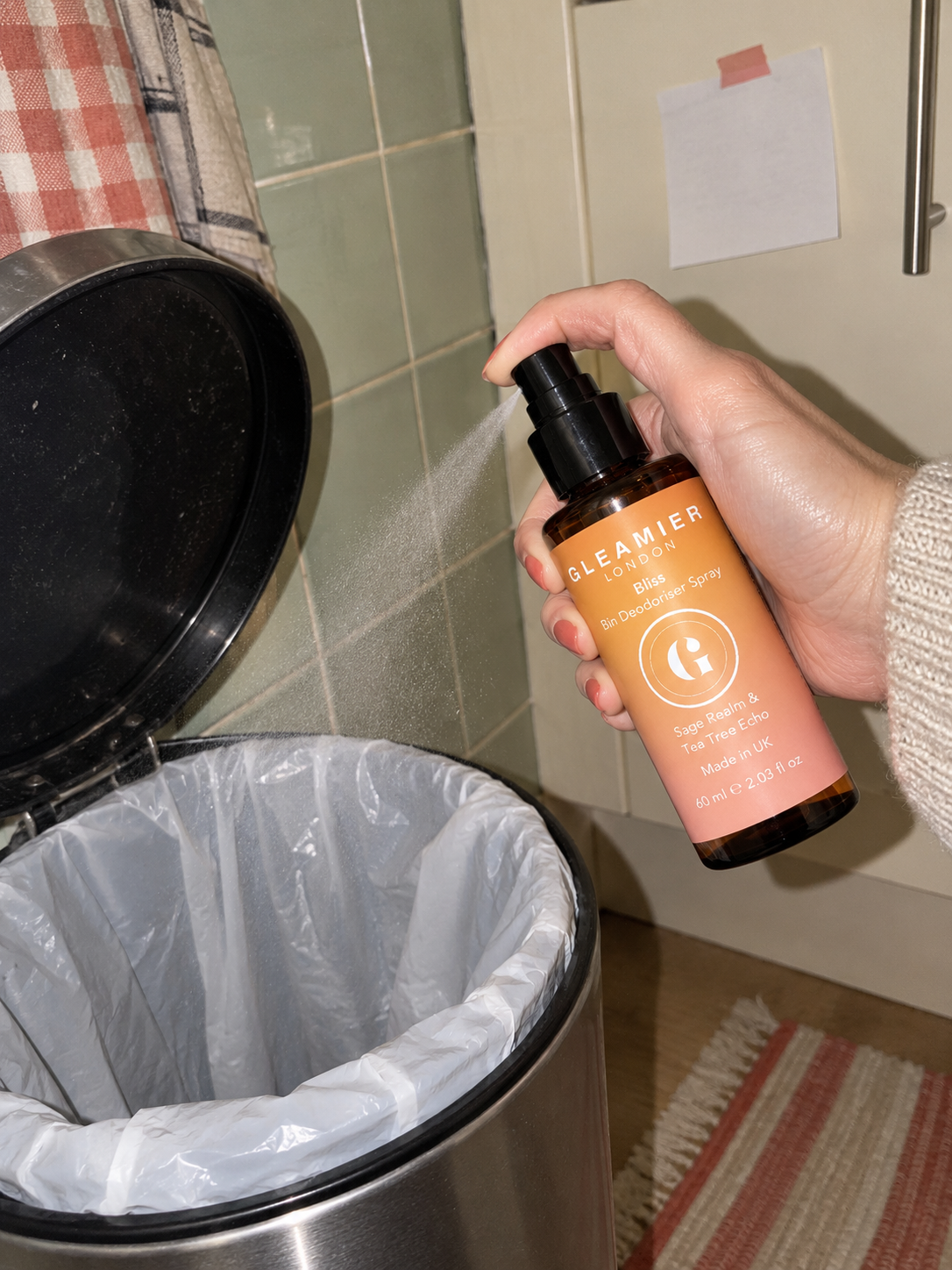 Hand spraying Gleamier Bliss bin deodoriser into a freshly lined kitchen bin.