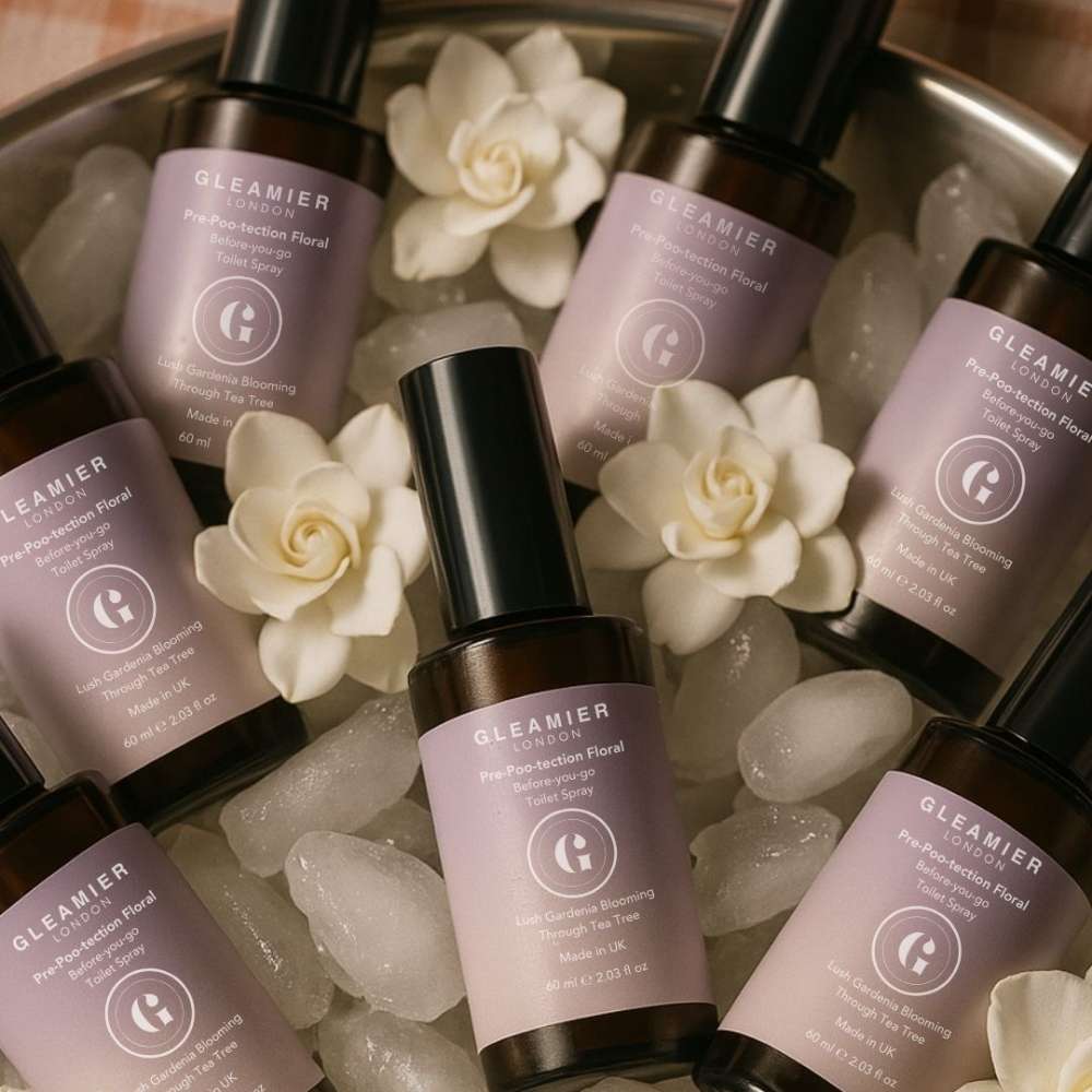 Flatlay of Gleamier toilet sprays in a chilled floral setting — gentle pre-poo protection without synthetic scent overload.