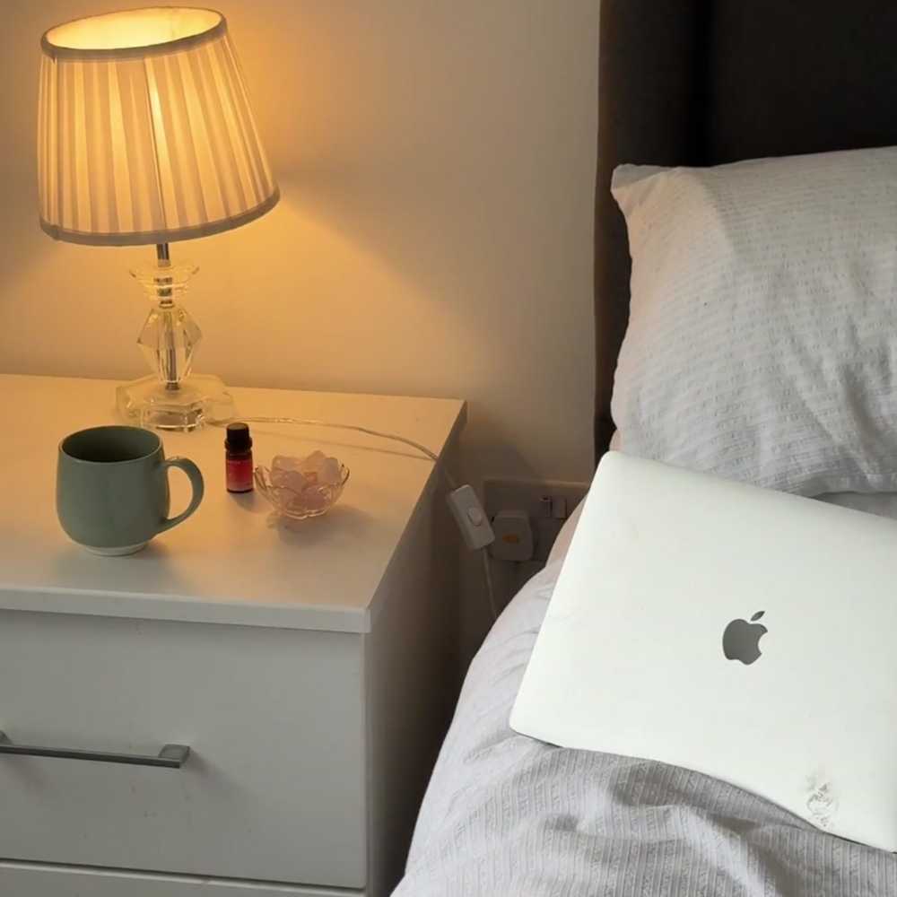 Natural stone diffuser setup on a nightstand beside bed and laptop.